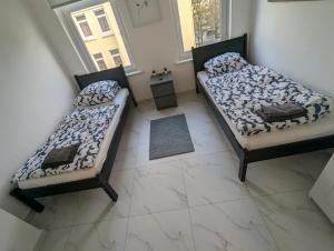 two beds in a room with a tiled floor at Nord Apartment 8 Moderne Ferienwohnung mit Regendusche & Fußbodenheizung in Bremerhaven