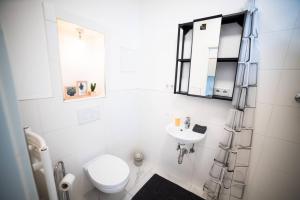 a white bathroom with a toilet and a sink at Nord Apartment 8 Moderne Ferienwohnung mit Regendusche & Fußbodenheizung in Bremerhaven