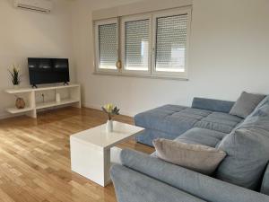 a living room with a blue couch and a tv at Ventana Pool Apartments - Stara Novalja in Stara Novalja