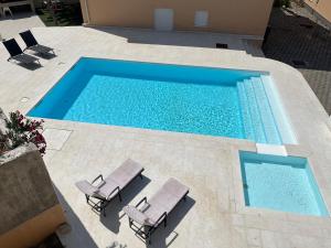 an overhead view of a swimming pool with two lounge chairs at Ventana Pool Apartments - Stara Novalja in Stara Novalja