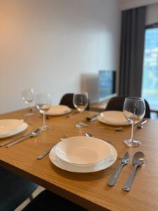 a wooden table with empty plates and wine glasses at Apartament KTW3 in Katowice +10 photos