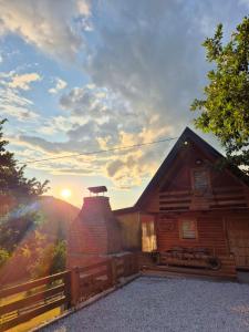 a wooden cabin with a sunset in the background at Zelena čarolija in Bioštica +6 photos