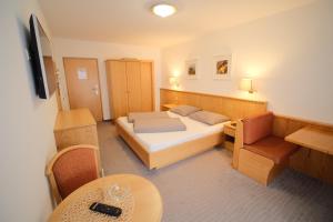 a small room with a bed and a table and chairs at Alpshotel Bergland in Pfelders