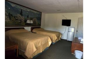 a hotel room with two beds and a flat screen tv at Hospitality Inn By Belvilla Selma US 80 AL in Selma