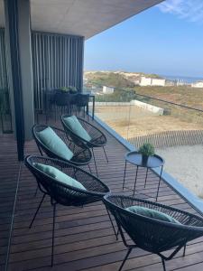 a deck with chairs and tables and a view of the beach at LUX BeACH in Praia da Barra
