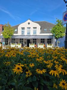 un campo de flores amarillas frente a un edificio en 1851 Bar - Hotel - Cinema, en Wijk bij Duurstede