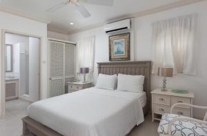 une chambre blanche avec un lit et une chaise dans l'établissement Cassia Heights 29 Royal Westmoreland, à Saint James