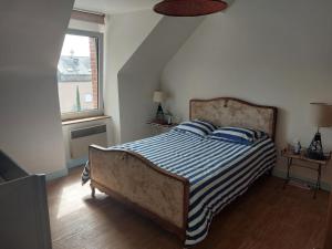 a bedroom with a bed with a striped comforter and a window at Maison de village au Linkin in Perros-Guirec