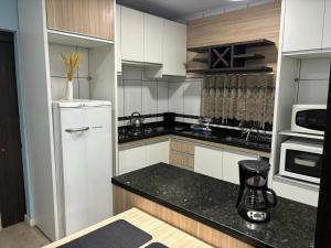 a kitchen with a white refrigerator and a microwave at Estúdio Moderno em frente à Rodoviária in Guarapuava