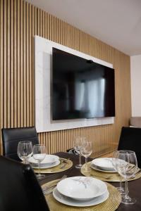 a table with plates and glasses and a television on a wall at Petit cocon à 2 pas d'Orly-Paris in Athis-Mons
