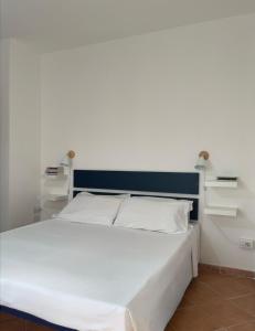 - un lit blanc avec une tête de lit bleue et des draps blancs dans l'établissement Design apartments - P, à Siniscola