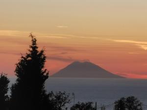 a mountain in the ocean at sunset at Villa Paradise in Capo Vaticano
