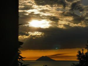 una puesta de sol sobre el océano con una montaña en el fondo en Villa Paradise, en Capo Vaticano