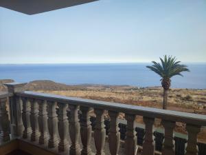 a balcony with a palm tree and the ocean at Villa las Cruces in Alajeró
