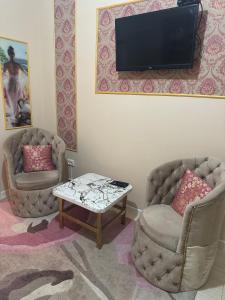 sala de estar con 2 sillas y TV en la pared en Aeroport Rooms, en Chişinău