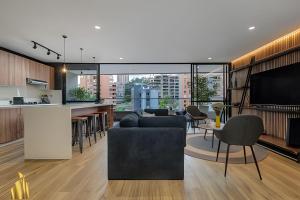een woonkamer en een keuken met een bank en een televisie bij Life 801 - Exclusive & Bright Apt/pool/gym/balcony in El Poblado
