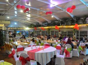 a banquet hall with tables and chairs with red bows at Tebu Hotel Bandung in Bandung
