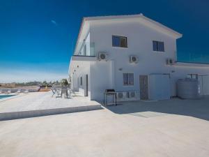 ein weißes Gebäude mit einer Terrasse und einem Tisch in der Unterkunft Villa Ioanni Chrysos - Luxury And New 6 Bedroom Protaras Villa in Protaras