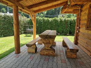 a picnic table and benches under a wooden pavilion at Zrub pri Hrone in Brezno