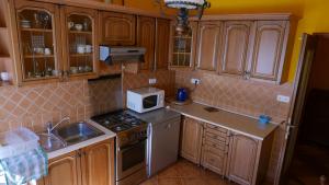 uma cozinha com armários de madeira, um fogão e um micro-ondas em Lipták Vendégház em Tokaj