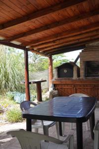 Una mesa y sillas en un patio con un horno al aire libre. en Cabañas Don Fernando, en Santa Rosa de Calamuchita
