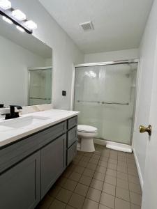 a bathroom with a sink and a toilet and a mirror at By Popular Demand - Houston in Houston