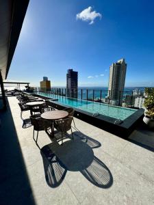 a balcony with tables and chairs on a building at UNU 405 Loft Luxury Corredor da Vitória: piscina + in Salvador +27 photos