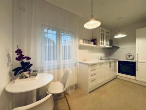 a kitchen with white cabinets and a table and chairs at Serafina central Apartment in Satu Mare