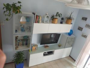 a living room with a tv and white shelves at Appartamento Riviera Trilocale wifi e parcheggio privato in Ventimiglia
