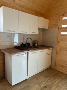 a kitchen with white cabinets and a sink at Zacisze Za Lasem in Jarosławiec