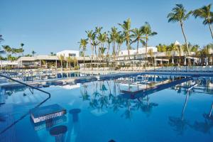 a large swimming pool with palm trees in the background at Riu Bambu - All Inclusive in Punta Cana