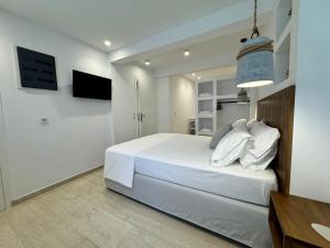a bedroom with a large white bed and a television at Kalami in Kokkari