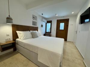 a bedroom with a large white bed and a television at Kalami in Kokkari