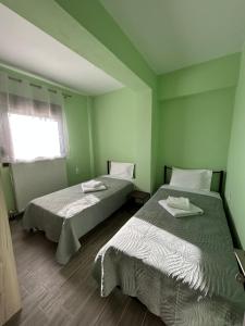 two beds in a room with green walls at Konitsa Escape Apartment in Konitsa