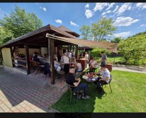 a group of people sitting at tables in the grass at Casa la Helesteu in Ocnele Mari