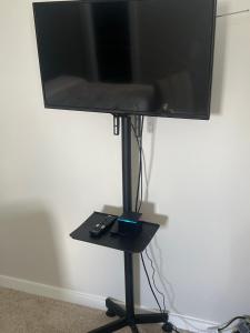 a flat screen tv on a stand with a remote control at Nanashortlet in Rosenberg