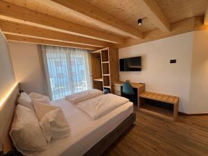 a bedroom with a bed and a desk with a television at Fiemme in Vista in Ziano di Fiemme