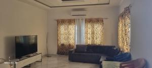 a living room with a couch and a flat screen tv at la maison sympa du pape saoudien in Kika