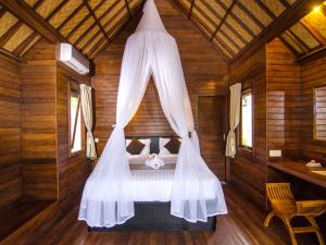 un dormitorio con una cama con mosquitera en Cassava Bungalow, en Nusa Lembongan