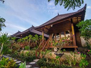 Casa de madera con balcón y algunas plantas en Cassava Bungalow, en Nusa Lembongan