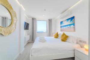 a white bedroom with a large white bed and a mirror at Blue Gold Escape - Ocean view, airco, heated pool in Adeje