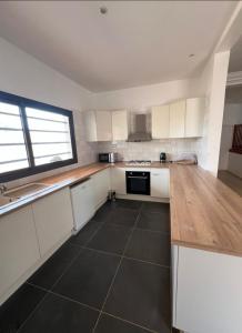 a kitchen with white cabinets and a black tile floor at Villa Le charme de Somone in Somone