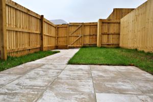 a wooden fence with a sidewalk and grass at Lower Townhouse, Exeter in Alphington