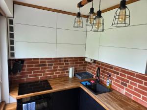 eine Küche mit weißen Schränken und einer Ziegelwand in der Unterkunft Apartament 3 pokoje in Słupsk