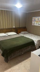two beds in a bedroom with a green blanket at Morada da Floresta in Gramado