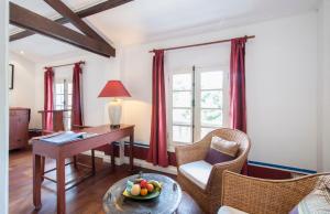 a living room with a desk and a table and chairs at The Belle Rive Boutique Hotel in Luang Prabang