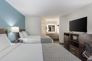 a hotel room with two beds and a flat screen tv at SureStay Plus Hotel by Best Western Asheboro in Asheboro