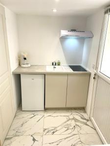 una cucina bianca con un lavello e un bancone di Havre de Paix proche Paris et Disney a Saint-Maur-des-Fossés