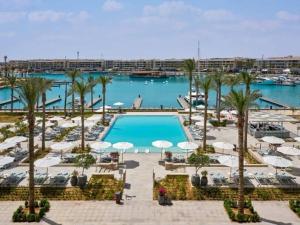 uitzicht op een zwembad met palmbomen en stoelen bij Apartment at Vida Marina Marassi in El Alamein