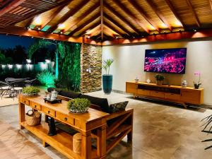 a living room with a couch and a tv on a wall at Recanto Quinta das Palmeiras, Casa com Piscina Aquecida, até 16 pessoas, Perto dos Parques, Olímpia-SP in Olímpia